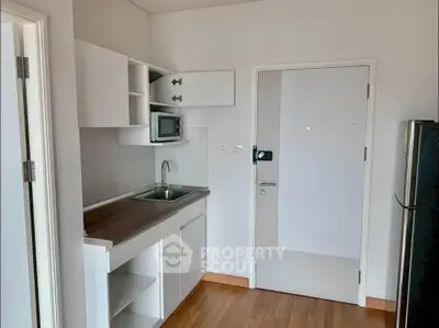Compact kitchen with modern cabinetry and stainless steel sink in a cozy apartment.