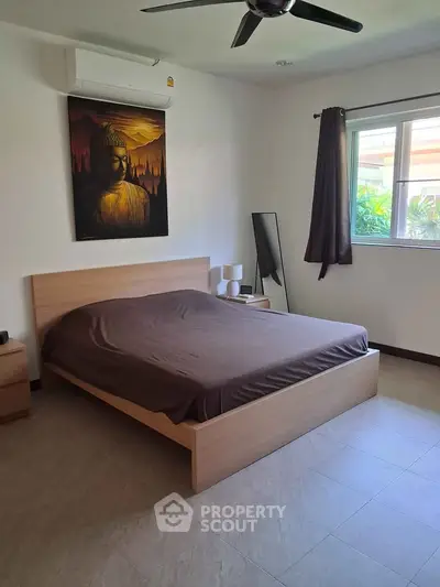 Spacious bedroom with modern decor and natural light, featuring a stylish bed and serene artwork.