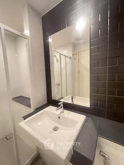 Modern bathroom with sleek black tiles and spacious shower area