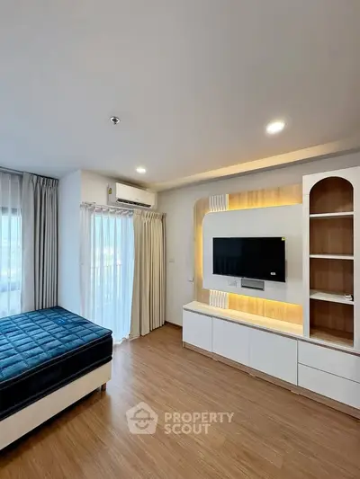 Modern bedroom with built-in TV unit and large windows for natural light