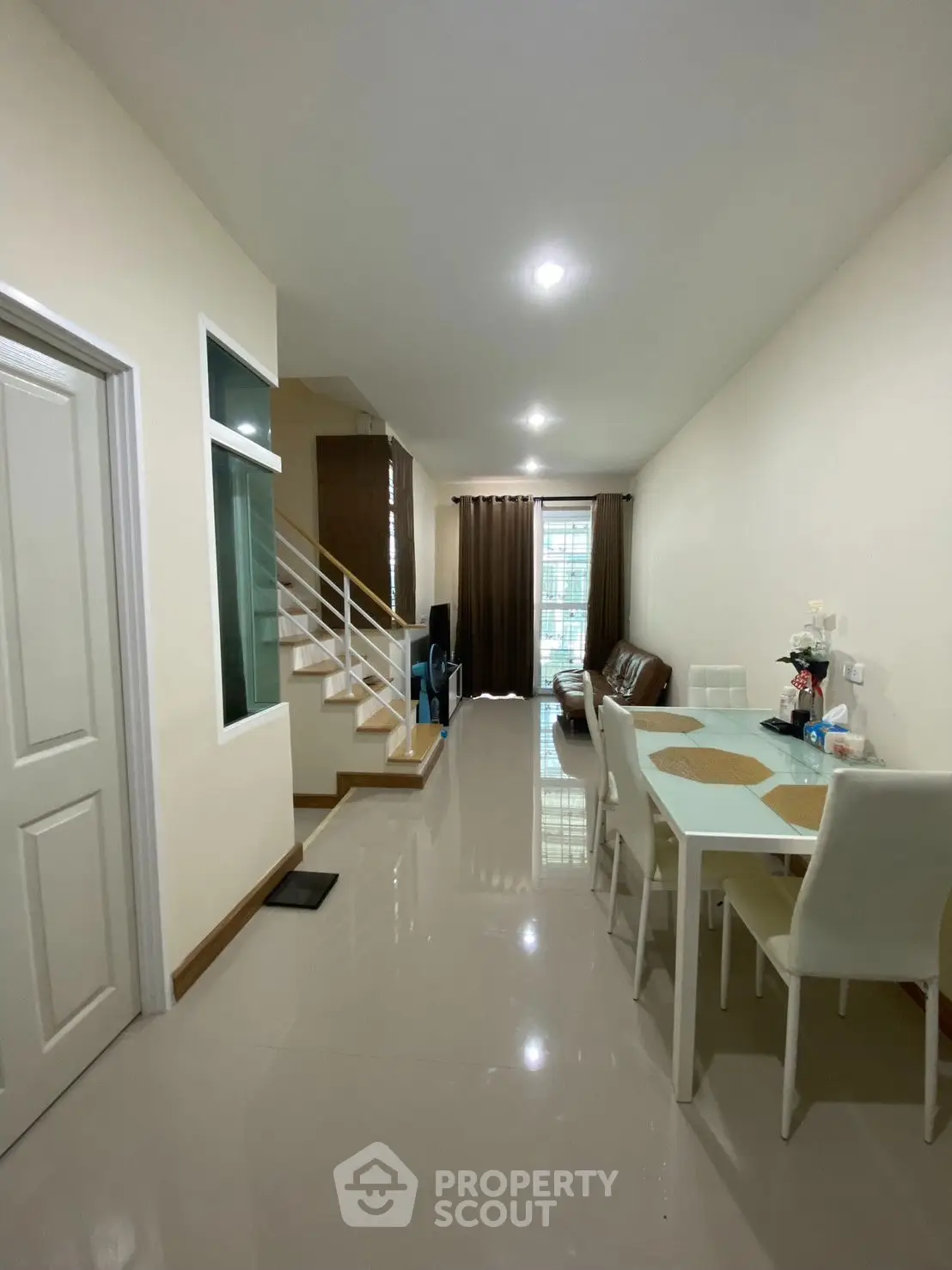 Modern living room with dining area and staircase in a cozy home setting.