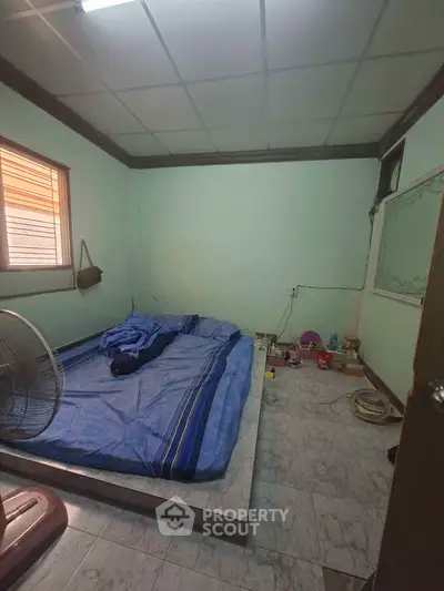 Cozy bedroom with minimalist decor and natural light, featuring a simple bed setup and tiled flooring.