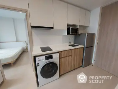 Modern compact kitchen with washing machine and fridge in cozy apartment