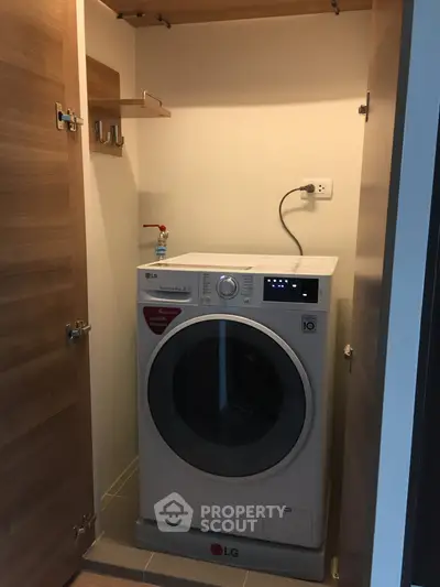 Compact laundry space with modern LG washing machine in wooden cabinet.