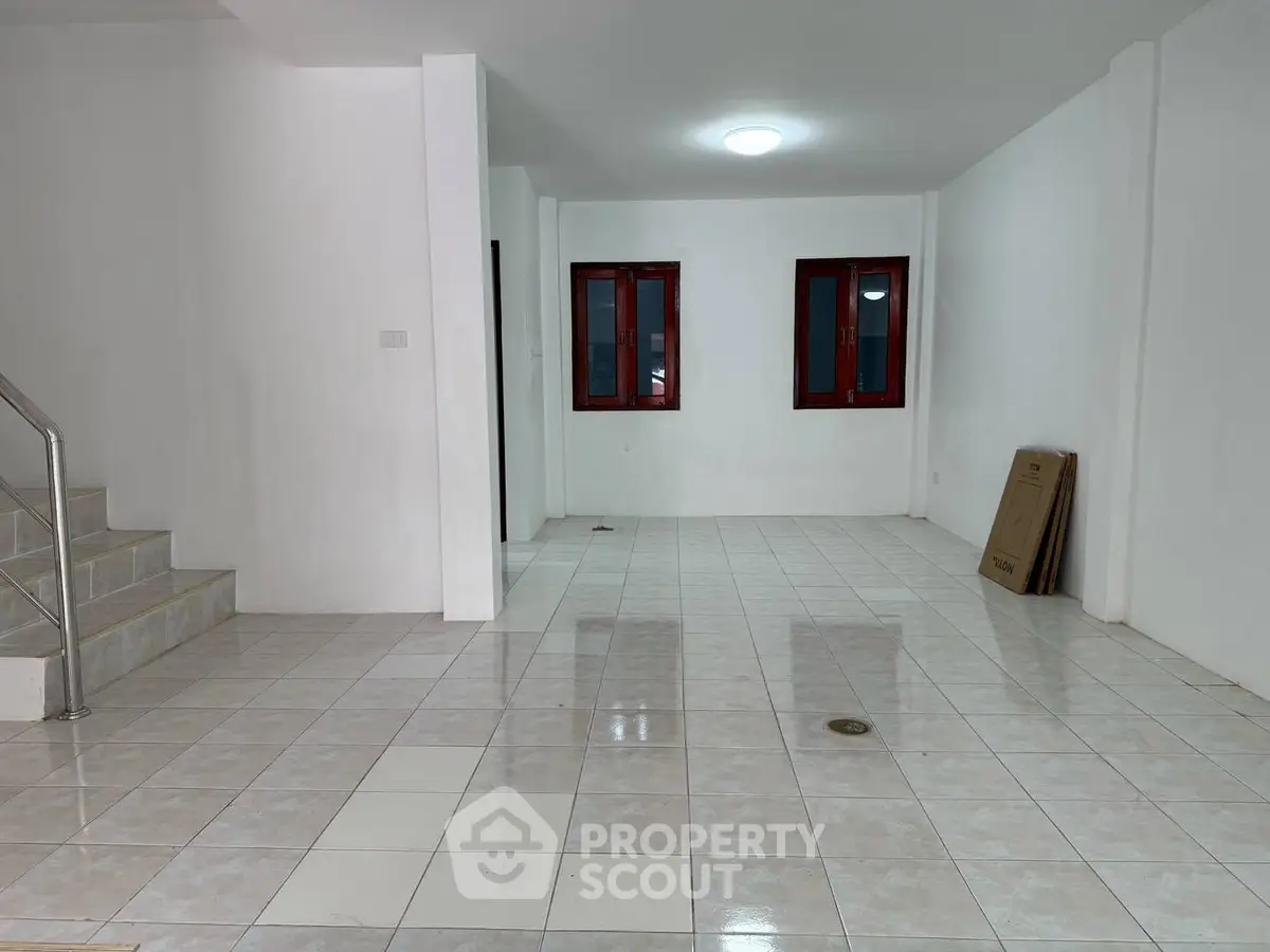 Spacious empty room with tiled floors and staircase, ready for customization.