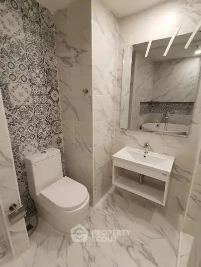 Modern bathroom with stylish tiles and sleek fixtures, featuring a wall-mounted sink and contemporary toilet.