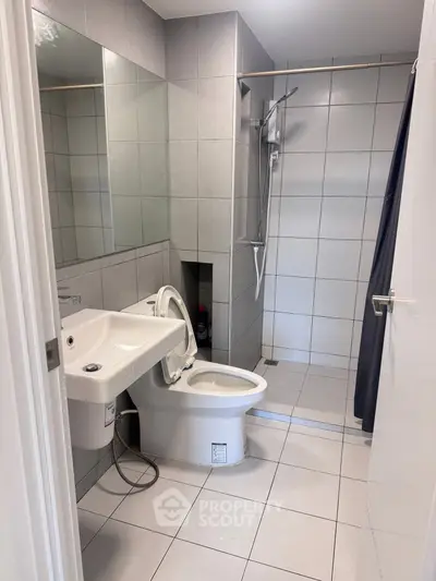 Modern bathroom with sleek tiles and walk-in shower in contemporary apartment.