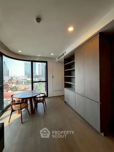 Modern living room with city view, featuring sleek furniture and large windows.