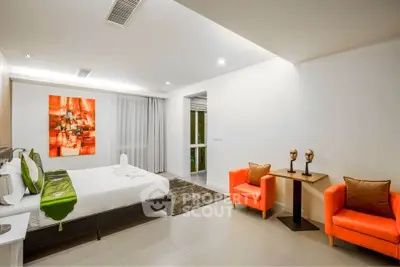 Modern bedroom with vibrant orange chairs and abstract art in luxury apartment