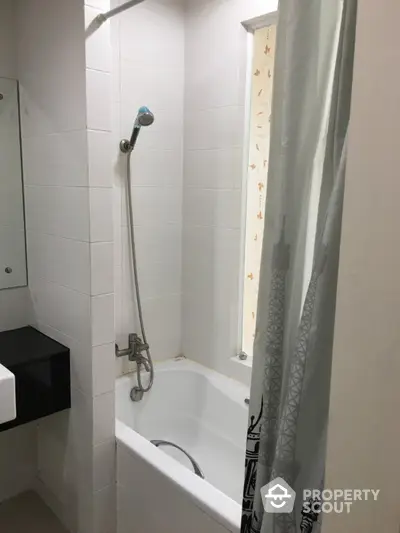 Modern bathroom with sleek white tiles and a bathtub with shower curtain.