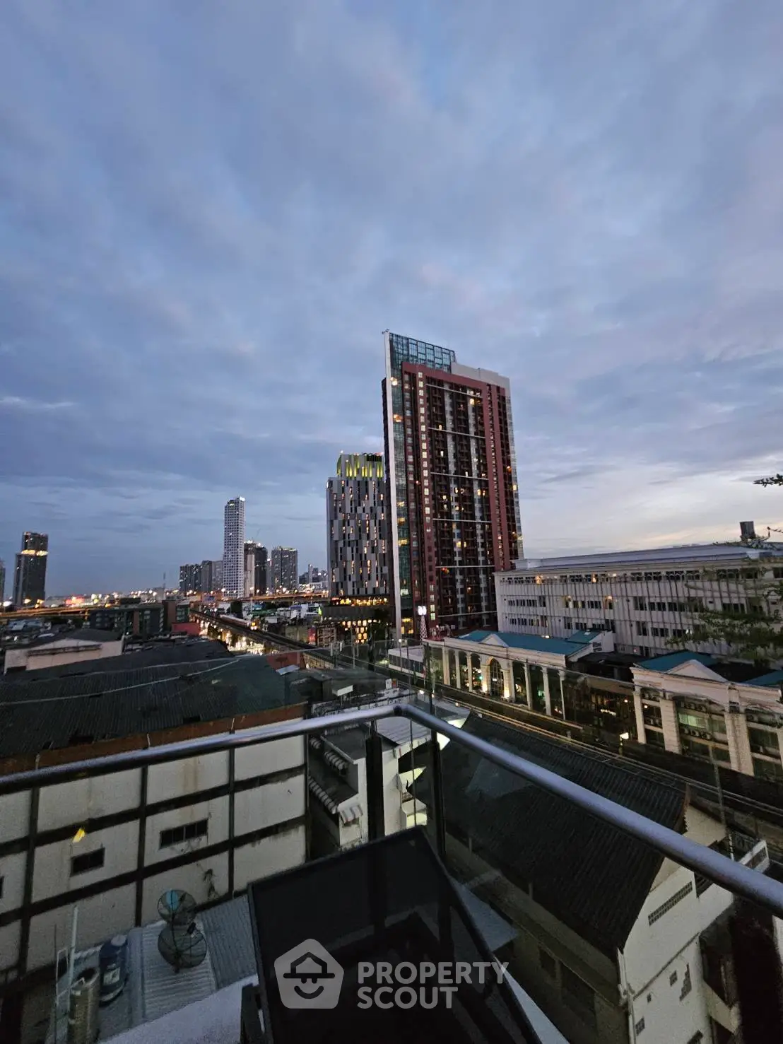 Stunning cityscape view from a high-rise balcony at dusk, showcasing urban skyline and modern architecture.