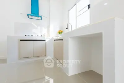 Modern kitchen with sleek design, featuring gas stove and ample natural light.