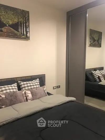 Cozy bedroom with modern decor and mirrored wardrobe in stylish apartment.