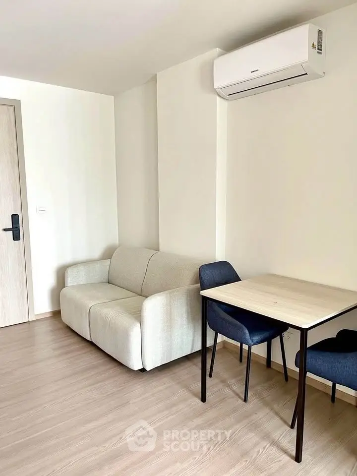 Modern living room with cozy sofa and dining table, featuring sleek air conditioning unit.