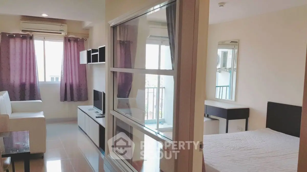 Modern apartment interior with living room and bedroom, featuring sleek furniture and natural light.