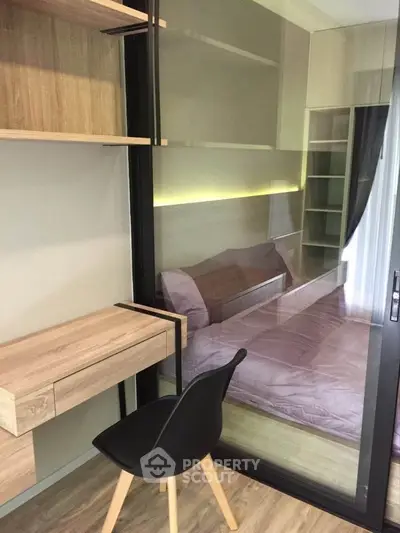 Modern bedroom with glass partition and stylish wooden desk in a cozy apartment.