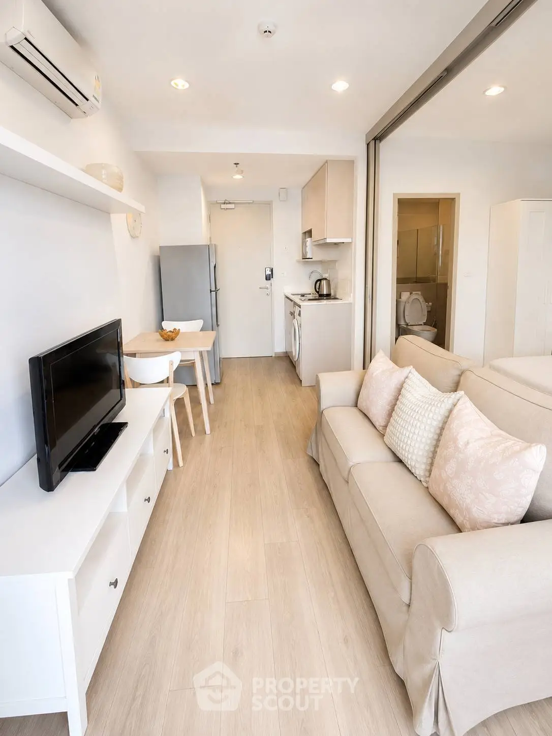Modern living room with open kitchen, featuring cozy sofa and dining area, perfect for urban living.