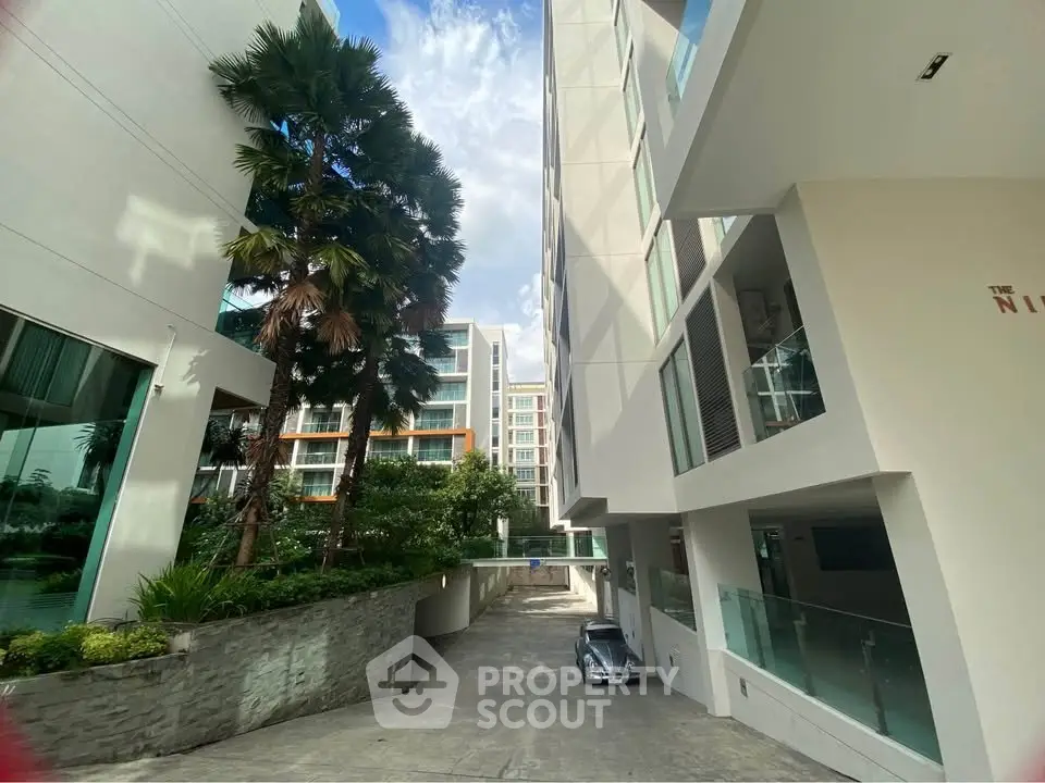 Modern apartment building exterior with lush greenery and sleek architecture.