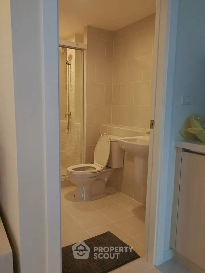 Modern bathroom with sleek design and neutral tiles, featuring a shower and toilet in a compact space.