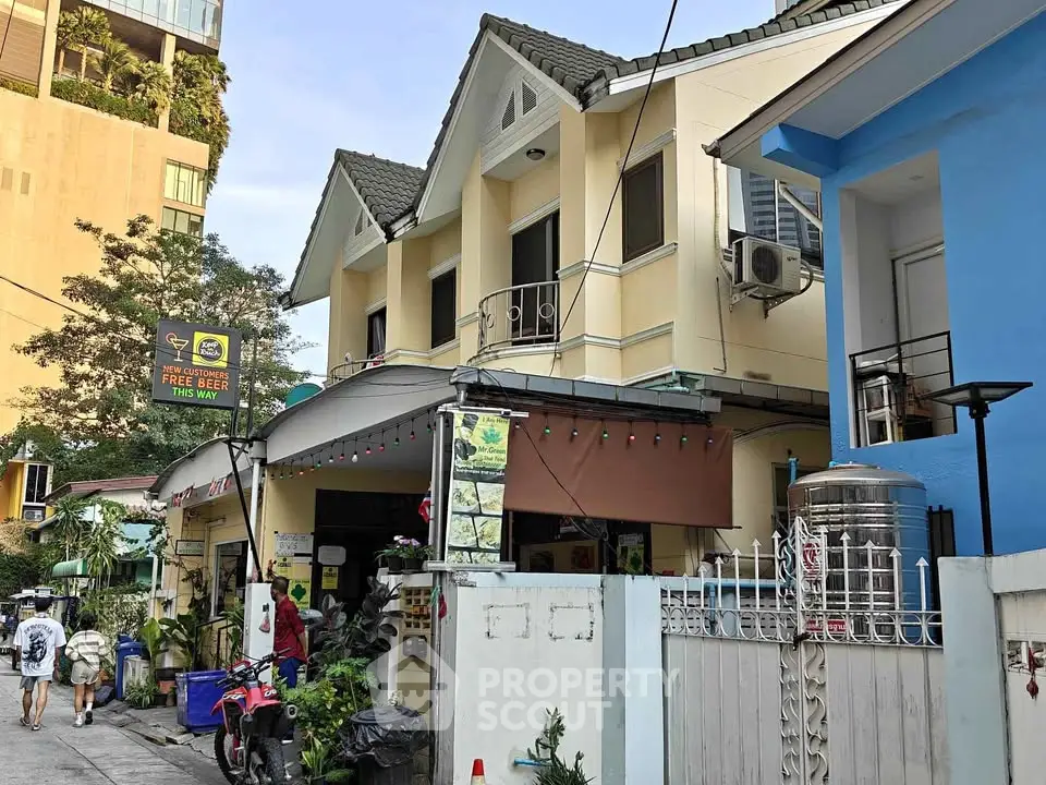 Charming two-story residential building with unique roof design and vibrant exterior colors.