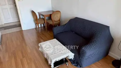 Cozy living room with wooden flooring, stylish sofa, and elegant dining set.