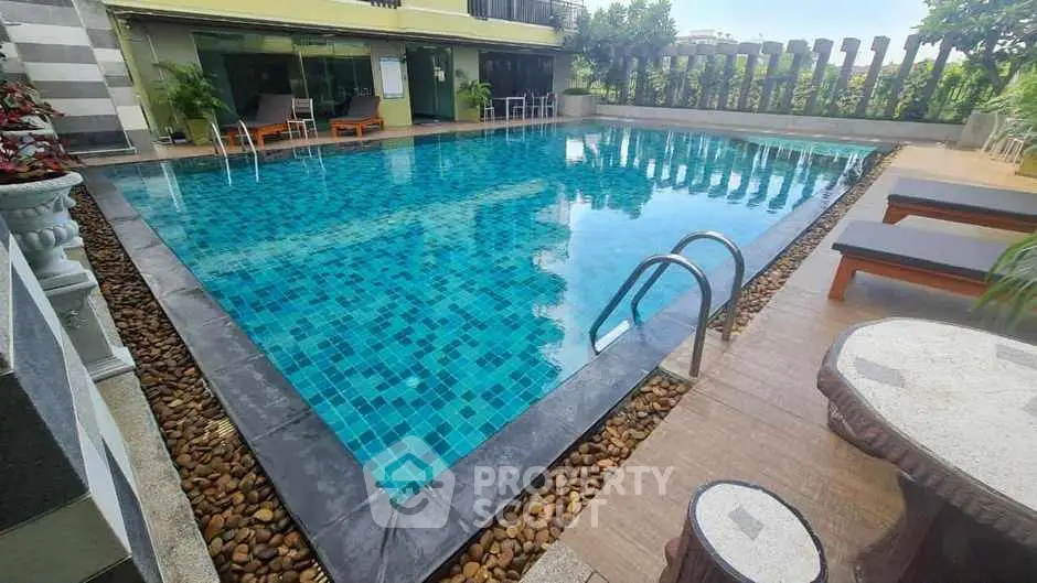 Luxurious outdoor pool area with stylish seating and lush greenery, perfect for relaxation and leisure.