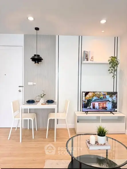 Modern living room with stylish decor and dining area, featuring a sleek TV setup and elegant lighting.