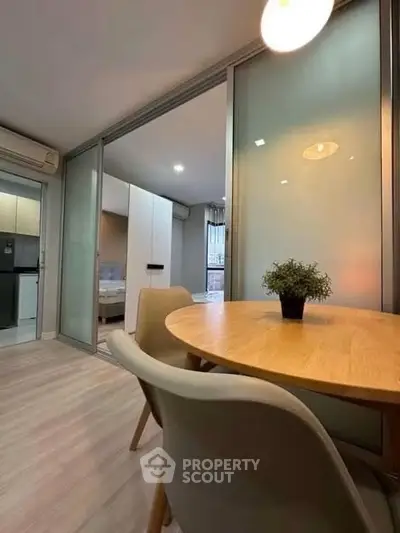 Modern apartment interior with dining area and sliding glass doors leading to bedroom.