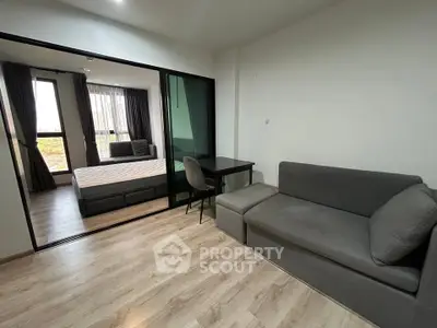 Modern studio apartment with cozy living area and bedroom, featuring sleek furniture and natural light.