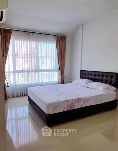 Bright and airy bedroom with large window and elegant curtains in modern home.