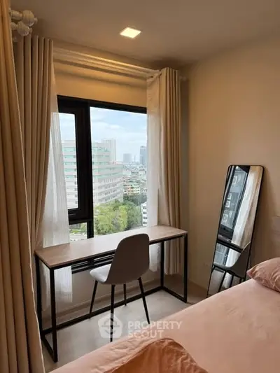 Cozy bedroom with city view, featuring a modern desk and chair by the window, perfect for work or study.