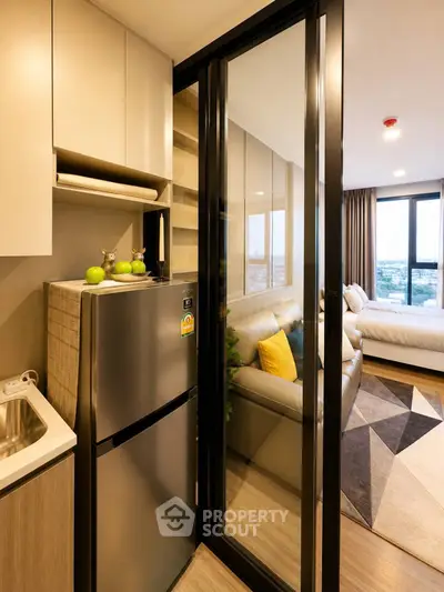 Modern studio apartment with sleek kitchen and cozy living area, featuring large windows and stylish decor.