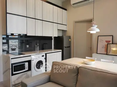 Modern kitchen with integrated appliances and stylish decor in open-plan living area.