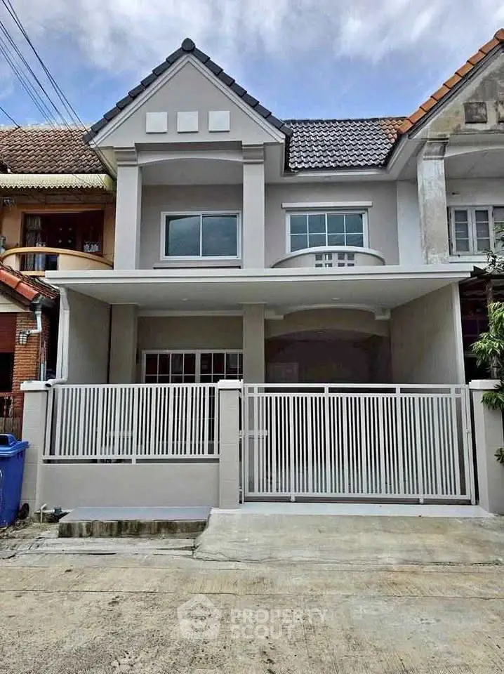 Charming two-story townhouse with modern facade and gated entrance in a cozy neighborhood.