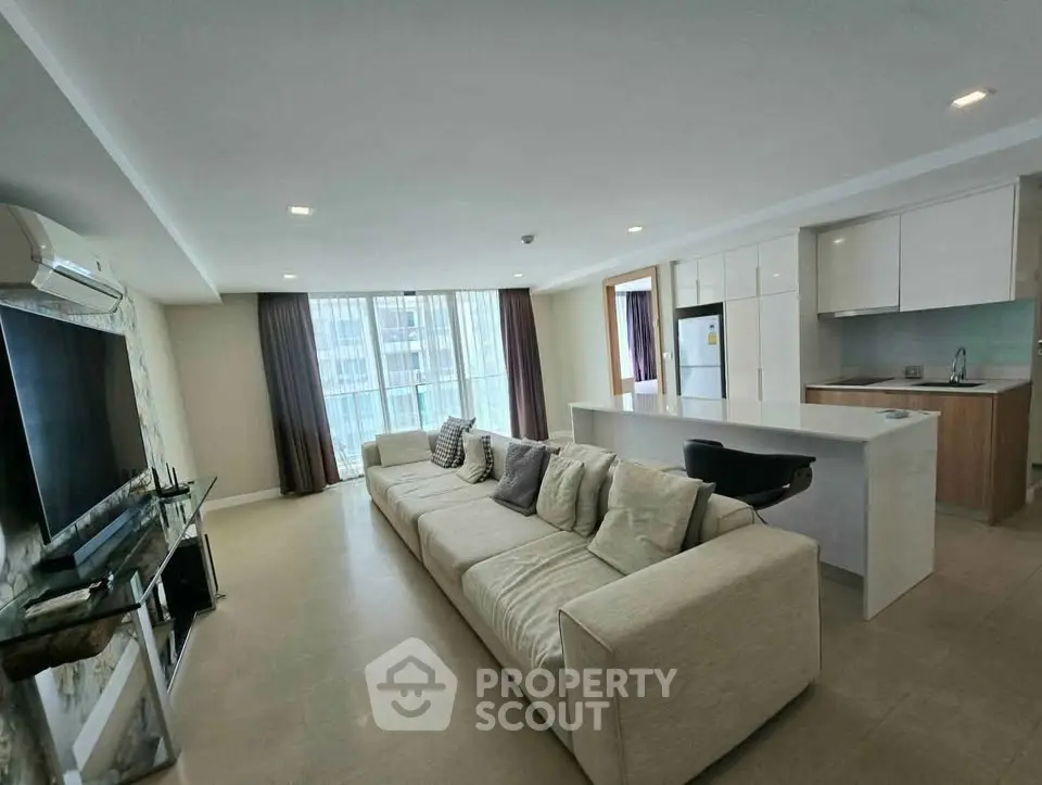 Spacious modern living room with open kitchen and large windows in a luxury apartment.