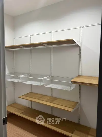 Spacious storage room with wooden shelves and wire baskets, ideal for organized living.