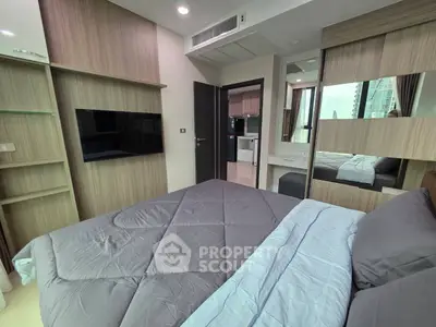 Modern bedroom with sleek design and city view, featuring a wall-mounted TV and stylish bedding.