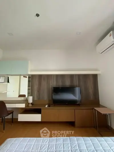 Modern bedroom with TV and air conditioning, featuring sleek wooden furniture and minimalist design.