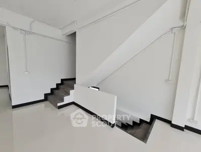 Modern minimalist staircase in a sleek white interior with polished floors.