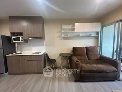 Modern studio apartment with sleek kitchen and cozy living area featuring a plush sofa and stylish shelving.