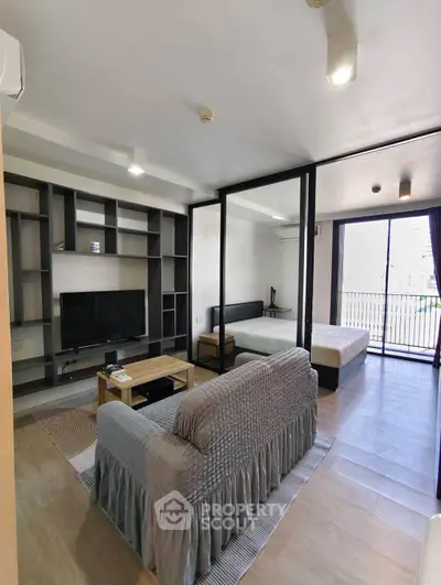 Modern studio apartment with open layout and balcony view, featuring stylish furnishings and ample natural light.
