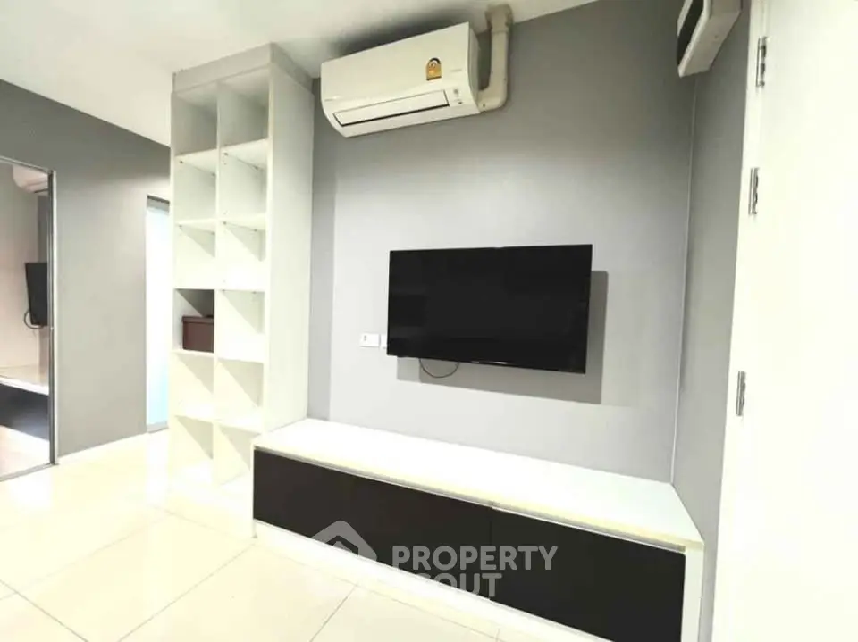Modern living room with wall-mounted TV and air conditioning unit, featuring sleek storage solutions.