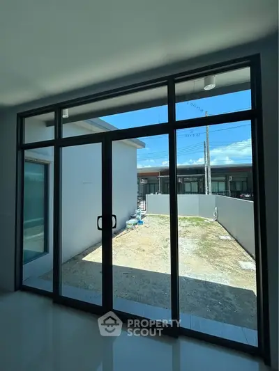 Spacious modern interior with large glass doors opening to a private outdoor area, perfect for natural light.