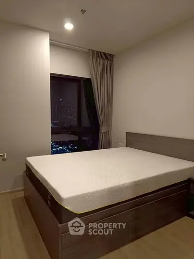 Modern bedroom with city view, featuring a sleek bed and elegant curtains, perfect for urban living.