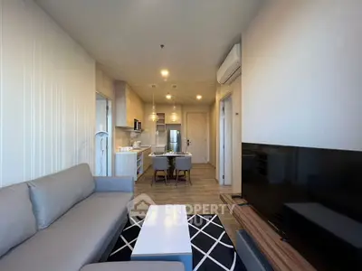 Modern living room with open kitchen, stylish furniture, and cozy ambiance.