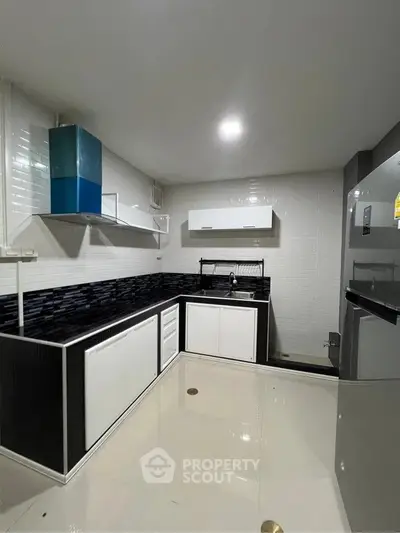 Modern kitchen with sleek black and white design, featuring a gas stove and ample storage.