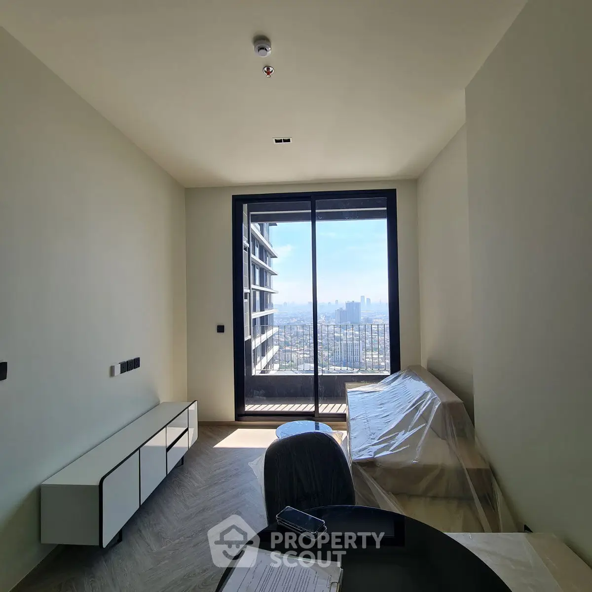 Modern living room with balcony and city view, featuring sleek furniture and natural light.