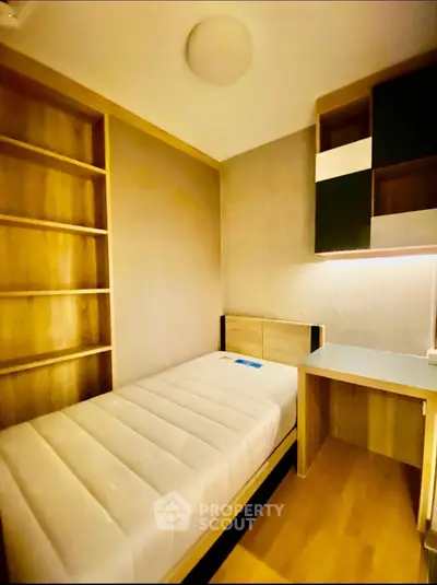 Cozy minimalist bedroom with built-in shelves and desk, perfect for compact living.