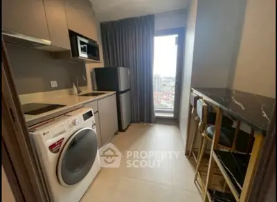 Modern kitchen with washing machine, fridge, and breakfast bar in a compact layout.