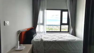 Modern bedroom with large window offering stunning city view, featuring cozy bed and sleek decor.